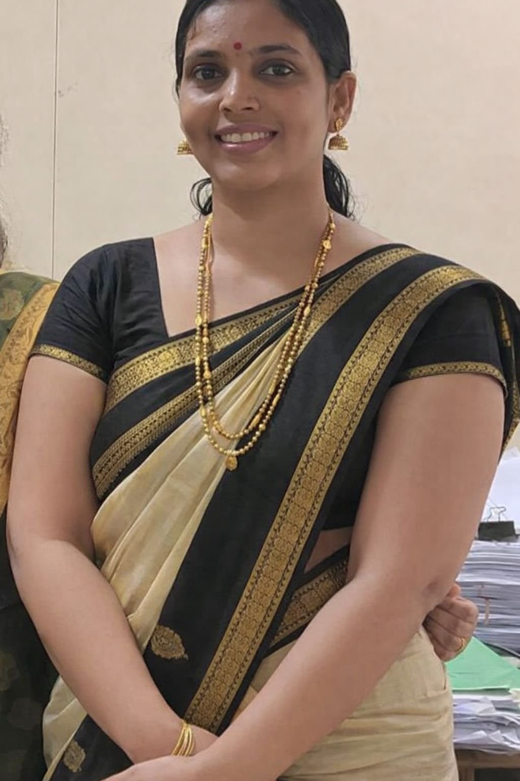 Lovely Indian bhabhi wearing black and gold saree with gold jewelry smiling
