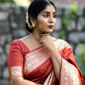 Desi woman in red saree with gold jewelry outdoors