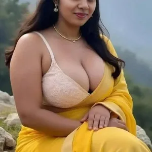South Indian woman in yellow saree sitting on rocky hillside