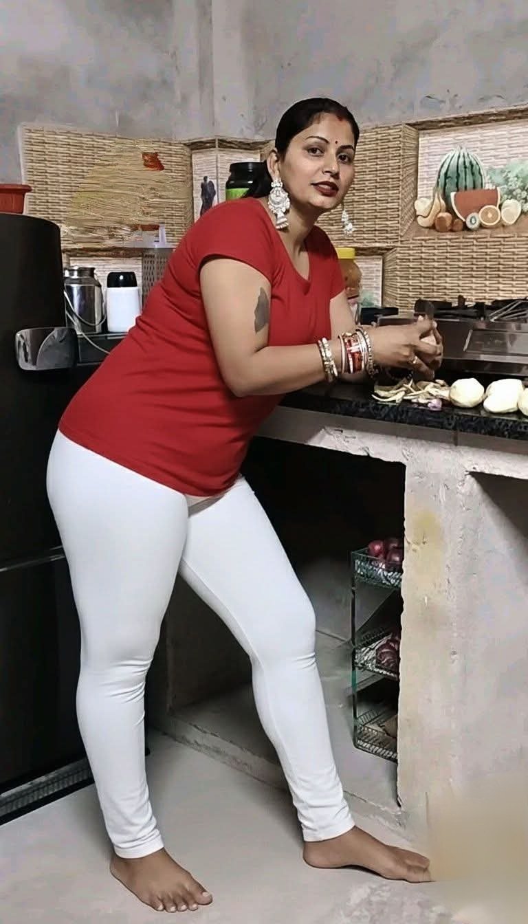 Curvy desi aunty in kitchen wearing red top and white leggings