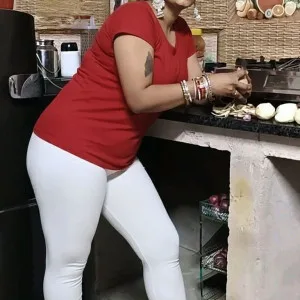 Curvy desi aunty in kitchen wearing red top and white leggings