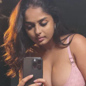Indian girl with long dark hair taking selfie in pink lace bra
