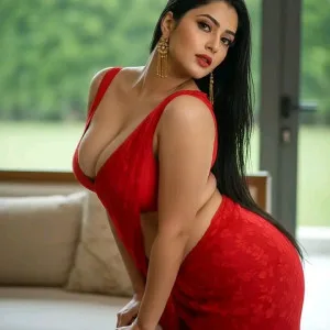 Curvaceous Indian bhabhi wearing red velvet dress with hand on hip in bedroom