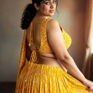 Curvy Indian woman in yellow lehenga posing seductively in studio