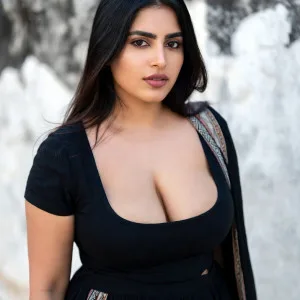 Confident Indian woman in black dress displaying cleavage outdoors
