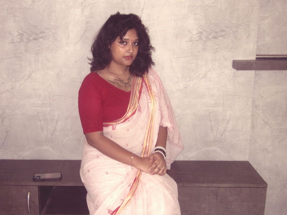 Telugu aunty in red blouse and pink saree seated gracefully