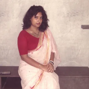 Telugu aunty in red blouse and pink saree seated gracefully