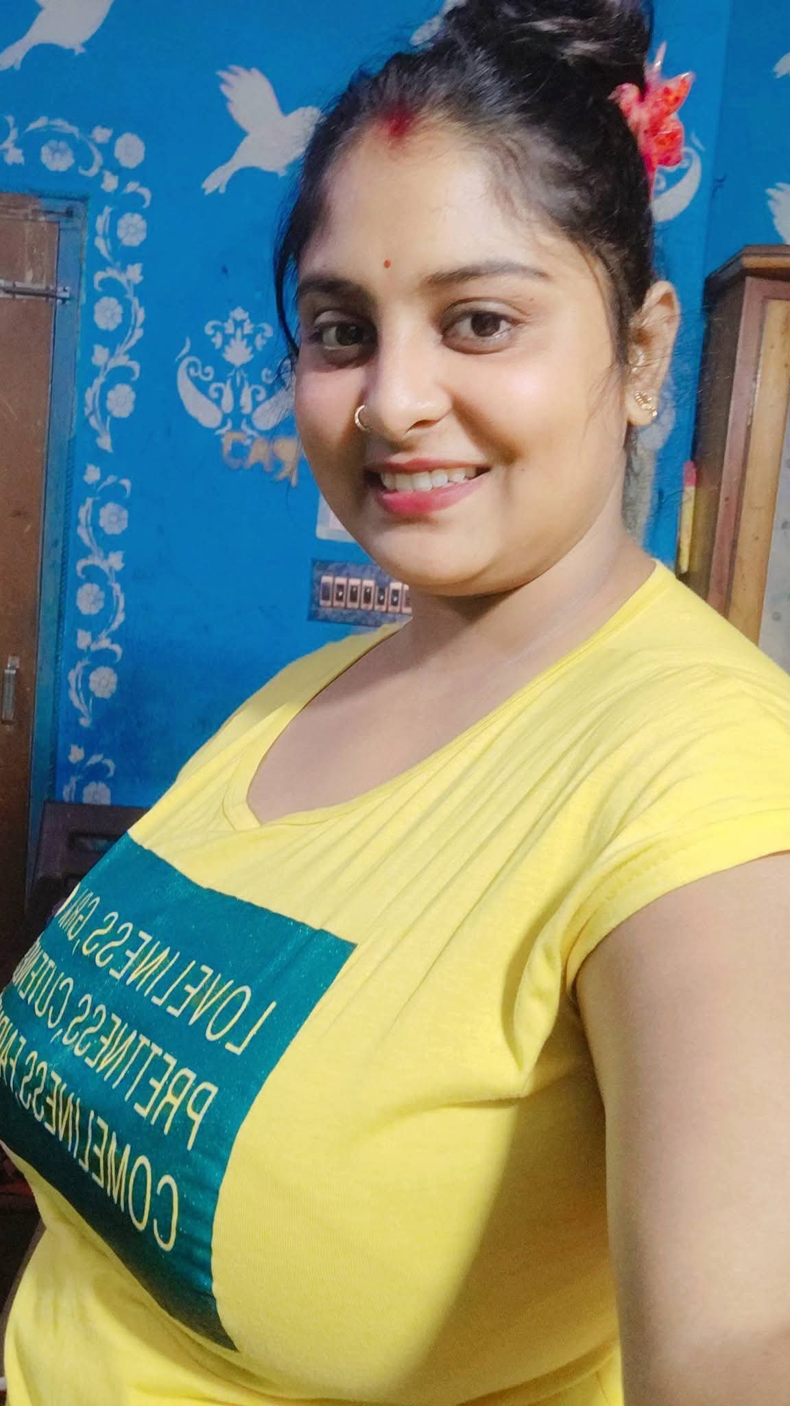 Delightful Indian bhabhi wearing yellow tee smiling warmly indoors
