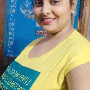 Delightful Indian bhabhi wearing yellow tee smiling warmly indoors