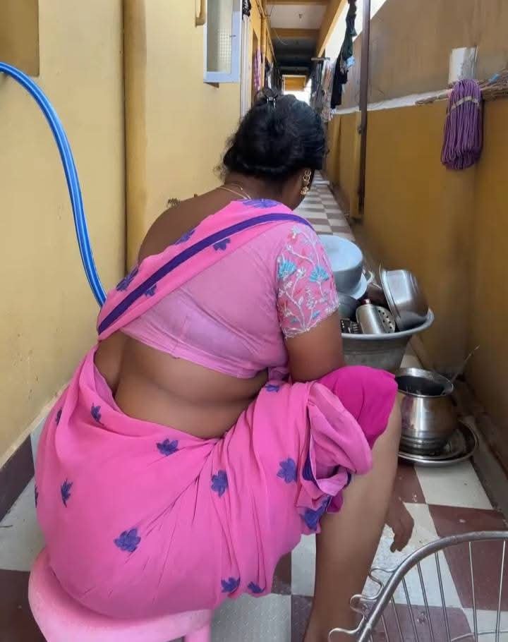 Curvy Indian aunty in pink saree bending during chores