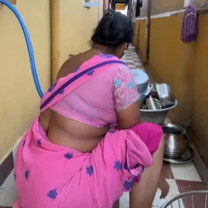 Curvy Indian aunty in pink saree bending during chores
