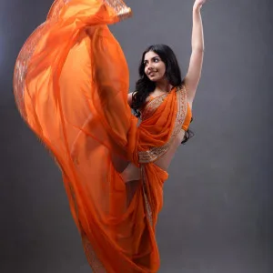 Gorgeous Indian bhabhi in orange saree posing seductively among rose petals