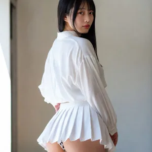 Youthful Asian girl in white school uniform turning back playfully