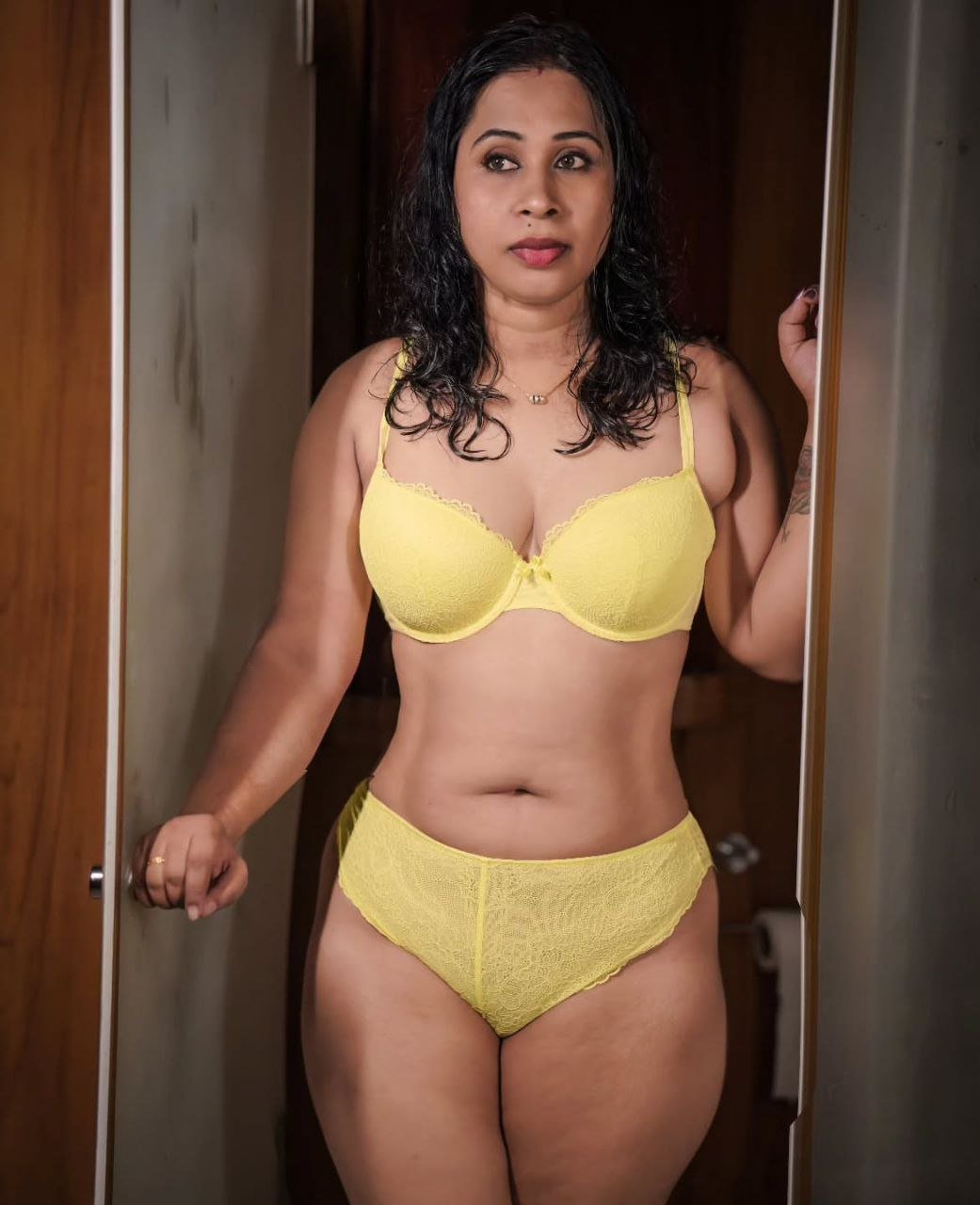 Voluptuous Indian bhabhi wearing yellow lace lingerie posing in doorway