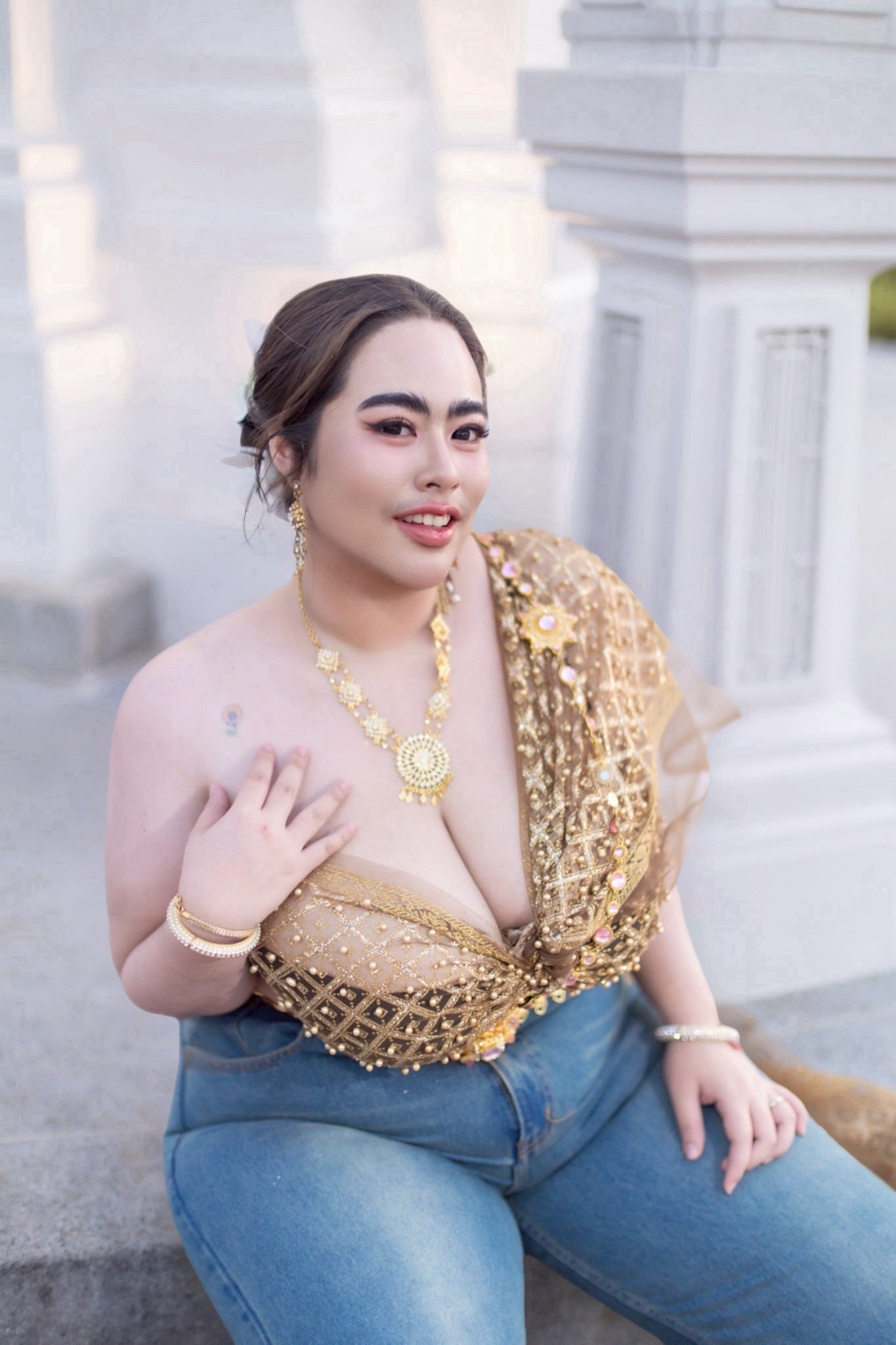 Captivating Indian bhabhi wearing gold blouse and jeans posing outdoors confidently